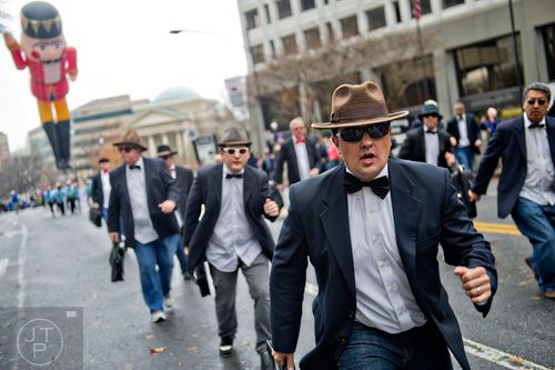 Ryan Jenkins (right) dances down Peachtree St. with the Briefcase Brigade during the 2014 Children's Christmas Parade in Atlanta on Saturday, December 6, 2014. 