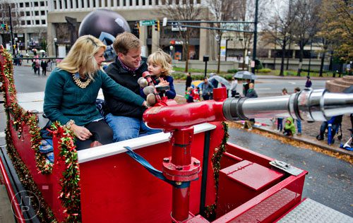 Kim Bishop (left), her husband Fred and son Knox ride a fire truck down Peachtree St. during the 2014 Children's Christmas Parade in Atlanta on Saturday, December 6, 2014. 