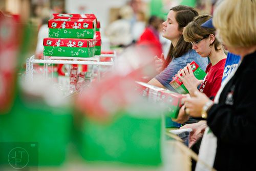 Anna Taylor (right) and Myrissa Webb sort through shoe boxes full of toys, school supplies and essentials that will be shipped to countries all over the world at the Samaritan's Purse packaging center in Suwanee for their Operation Christmas Child campaign on Tuesday, December 9, 2014. 