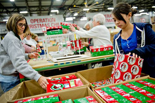 Shawn Cox (right) and Rose Graffius pick up shoe boxes full of toys, school supplies and essentials that will be shipped to countries all over the world before sorting through them at the Samaritan's Purse packaging center in Suwanee for their Operation Christmas Child campaign on Tuesday, December 9, 2014. 