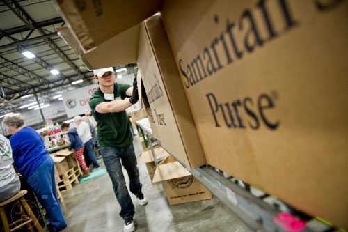 Titus Campbell (center) pushes boxes full of shoe boxes filled with toys, school supplies and essentials that will be shipped to countries all over the world at the Samaritan's Purse packaging center in Suwanee for their Operation Christmas Child campaign on Tuesday, December 9, 2014.