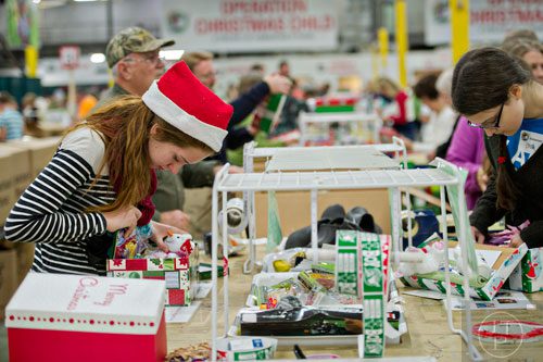 Sarah Klinect (left) sorts through a shoe box full of toys and essentials that will be shipped to countries all over the world at the Samaritan's Purse packaging center in Suwanee for their Operation Christmas Child campaign on Tuesday, December 9, 2014. 