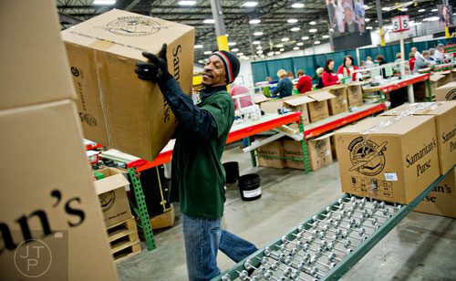 Joseph Quainoo (center) stacks a box filled with shoe boxes full of toys, school supplies and essentials that will be shipped to countries all over the world onto a pallet at the Samaritan's Purse packaging center in Suwanee for their Operation Christmas Child campaign on Tuesday, December 9, 2014. 