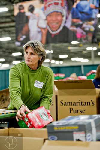 Frances Callison picks up a shoe box full of toys and essentials that will be shipped to countries all over the world before sorting through it at the Samaritan's Purse packaging center in Suwanee for their Operation Christmas Child campaign on Tuesday, December 9, 2014.
