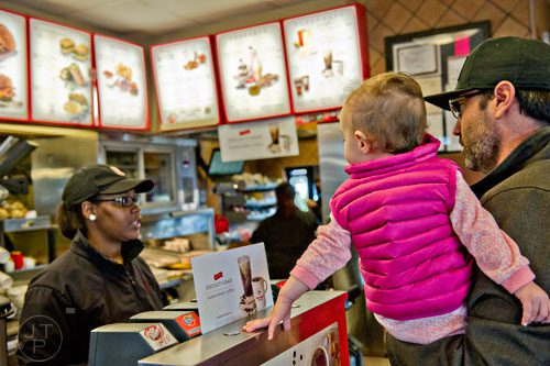 Colin McChesney (right) holds his daughter Evan as they order food from Crystal Amaker at the Chick-fil-A off of Camp Creek Parkway in East Point on Wednesday, December 10, 2014. 