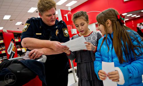 Brookhaven Police Maj. Linda Burke (left), Katerina Vassileva and Dulce Ballin look at Katerina's wish list as they shop during the first annual Brookhaven Police Shop with a Badge event at the Target off of North Druid Hills in Atlanta on Saturday, December 13, 2014. 