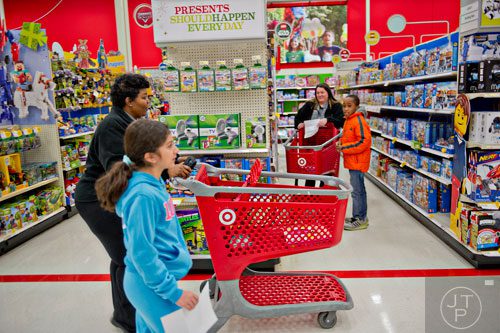 Joshua Alaman (right) shops with Brookhaven dispatcher Shannon Parham as Melissa Cambron passes by with dispatcher Yolanda Chandler during the first annual Brookhaven Police Shop with a Badge event at the Target off of North Druid Hills in Atlanta on Saturday, December 13, 2014. 