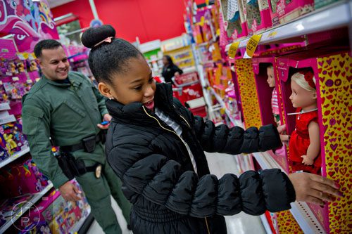 Soleil Jarrett (right) picks out a doll as she shops with Brookhaven Police Det. Johnny Alemany during the first annual Brookhaven Police Shop with a Badge event at the Target off of North Druid Hills in Atlanta on Saturday, December 13, 2014. 