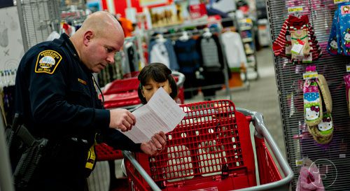 Brookhaven Police Lt. Eric Silveus (left) and Jessenia Segura look at her wish list as they shop during the first annual Brookhaven Police Shop with a Badge event at the Target off of North Druid Hills in Atlanta on Saturday, December 13, 2014. 