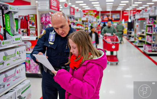 Brookhaven Police Ofc. Drake Ford (left) and Ashlyn Moody look at her wish list as they shop during the first annual Brookhaven Police Shop with a Badge event at the Target off of North Druid Hills in Atlanta on Saturday, December 13, 2014. 