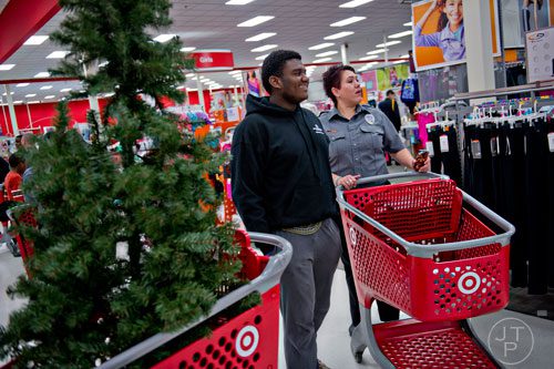 Kingston Handley (left) leaves the Christmas tree he picked out for his family as he continues to shop with Brookhaven dispatcher Stephanie Thompson during the first annual Brookhaven Police Shop with a Badge event at the Target off of North Druid Hills in Atlanta on Saturday, December 13, 2014. 