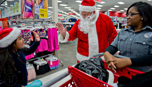 Santa Claus waves to Haidee Quechol (left) as she stands in line with Brookhaven dispatcher Myrianna Butler during the first annual Brookhaven Police Shop with a Badge event at the Target off of North Druid Hills in Atlanta on Saturday, December 13, 2014. 