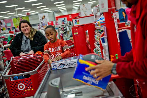 Joshua Alaman (center) takes gifts out of the shopping cart that he and Brookhaven dispatcher Shannon Parham (left) picked out for his family as Torraine Anglin rings up the purchases during the first annual Brookhaven Police Shop with a Badge event at the Target off of North Druid Hills in Atlanta on Saturday, December 13, 2014. 