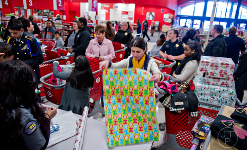 Blaga Djordjev (center) helps wrap presents during the first annual Brookhaven Police Shop with a Badge event at the Target off of North Druid Hills in Atlanta on Saturday, December 13, 2014. 