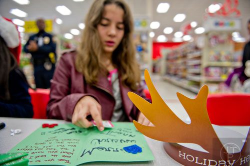 Melissa Ballin writes a thank you note to the Brookhaven police officer who helped her shop during the first annual Brookhaven Police Shop with a Badge event at the Target off of North Druid Hills in Atlanta on Saturday, December 13, 2014. 