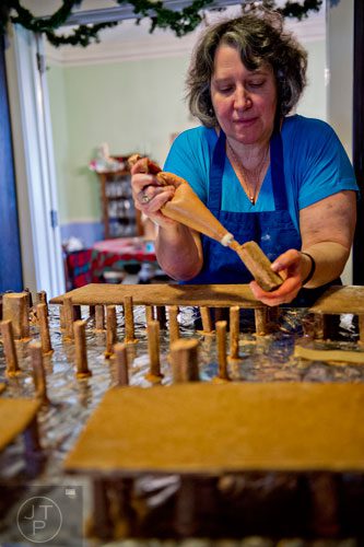 Emily Wert glues a piece of gingerbread using a special frosting as she works on a replica of Laketown from "The Hobbit" movies at her home in Atlanta on Friday, December 12, 2014. 