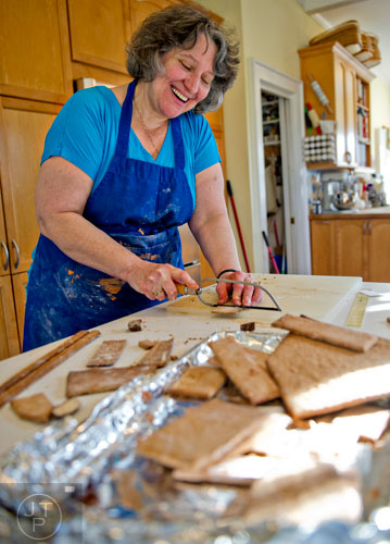Emily Wert uses a hack saw to cut gingerbread as she works on a replica of Laketown from "The Hobbit" movies at her home in Atlanta on Friday, December 12, 2014. 