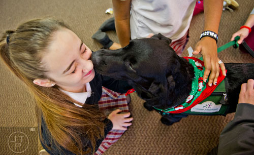 Haley Plant (left) is licked in the face by Wonton, a golden-labradoodle with the Canine Assistants program, as she takes a break from studying for final exams at Holy Innocents' Episcopal School in Atlanta on Friday, December 19, 2014.