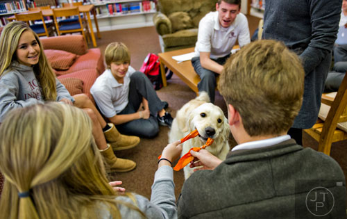 Adrianna Barry (left), Sean Brock, Baylor Rainbow, Harrison DeLong and Camryn Landis take a break from studying for final exams to play with Adidas, a golden retriever with the Canine Assistants program, at Holy Innocents' Episcopal School in Atlanta on Friday, December 19, 2014. 