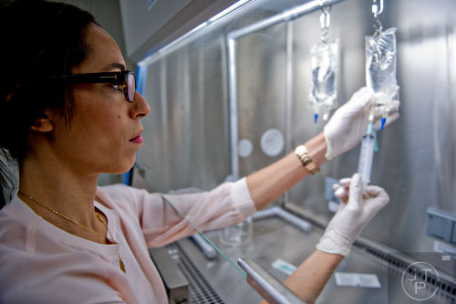 Dr. Hagar Badawy uses a syringe to extract medicine from a drip bag inside the pharmacy at the Atlanta Center for Medical Research on Wednesday, December 10, 2014. 