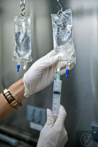 Dr. Hagar Badawy uses a syringe to extract medicine from a drip bag inside the pharmacy at the Atlanta Center for Medical Research on Wednesday, December 10, 2014.