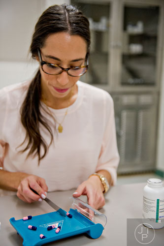 Dr. Hagar Badawy counts pills on a tray inside the pharmacy at the Atlanta Center for Medical Research on Wednesday, December 10, 2014.