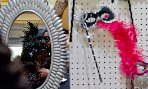 Rhonda Thompson (left) looks in a mirror as she tries on different masks during the 31st annual United Negro College Fund Mayor's Masked Ball at the Atlanta Marriott Marquis in downtown on Saturday, December 20, 2014. 