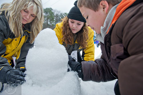 Stephanie Basile (left) builds a snowman with her grandchildren Savanna and C.J. Simpson during Snow Mountain at Stone Mountain Park on Sunday, December 21, 2014.