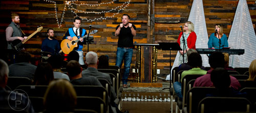 Pastor Josiah Potter (center) speaks to his congregation during Sunday worship service as he stands on stage with Ryan Williams (left), Nathan Lueke, James Brown, Lydia Shanks and Hannah Beth Potter at Crosspointe Church in Peachtree City on Sunday, December 21, 2014. 