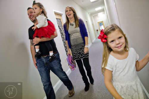 Pastor Josiah Potter (left) carries his daughter Sunday as he walks down the hall with his wife Jordan and other daughter Mercy after worship service at Crosspointe Church in Peachtree City on Sunday, December 21, 2014. 