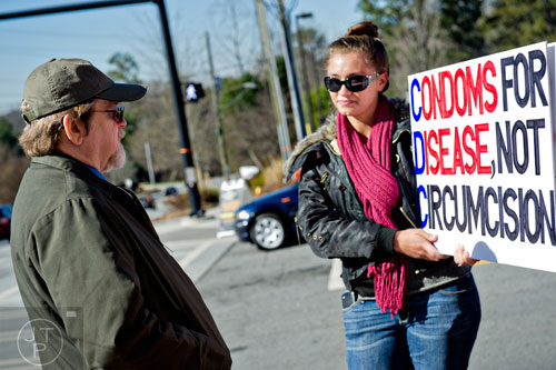 Terry Jackson (left) talks with Kelley Heitzman as she holds a sign against circumcision across the street from the Center for Disease Control in Atlanta on Friday, December 12, 2014.  