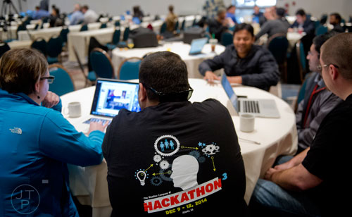 Zeeshan Khan (center) helps Robyn Weeks make last minute adjustments before helping pitch their team's app to a panel of judges during The Weather Channel's Hack-A-Thon at the Atlanta Marriott Northwest at Galleria on Friday, December 12, 2014. 