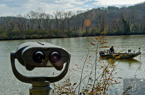 A pair of binoculars rise from the River Boardwalk Trail at the Chattahoochee Nature Center as Paul Jusiewicz fishes from his boat along the river in Roswell on Saturday, December 27, 2014. 