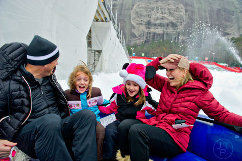 Scott (left), his wife Tamara (right) and their daughters Hannah and Kate ride the family tube down the hill during Snow Mountain at Stone Mountain Park on Sunday, December 21, 2014. 