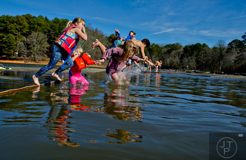 Kendall Grattan (left), her sister Annalee, Gracyn Potter and others hold hands as they jump into Lake Lanier during the 18th annual Polar Bear Plunge at the Lanier Canoe & Kayak Club in Gainesville on Thursday, January 1, 2015.