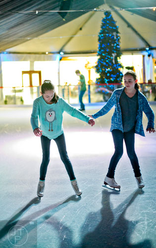 Mary Winer (left) holds hands with Bella Samuels as they try to skate backwards at the Southwest Rink at Park Tavern in Atlanta on Saturday, January 3, 2015. 