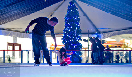 Chris Grumboski (left) reaches down to help his daughter Emily off of the ice at the Southwest Rink at Park Tavern in Atlanta on Saturday, January 3, 2015. 