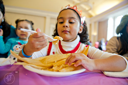 Miriam Patton (center) takes a bite of a freshly made tamale during the Three Kings Day Festival at the Atlanta History Center on Sunday, January 4, 2015. 