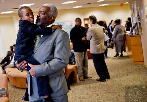 Michael Majette (center) holds one of his three sons Jimariyo as friends and family fill the lobby of the Fulton County Juvenile Courthouse in Atlanta before he and his wife finalize the adoption of  Jimariyo and his brothers Jimitrious and Jimarcus on Monday, December 29, 2014. 
