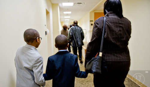 Jimariyo Majette (center) walks towards the courtroom of Chief Judge Bradley J. Boyd holding hands with his oldest brother Jimitrious (left) and their new mother Pam before finalizing the adoption process at the Fulton County Juvenile Courthouse in Atlanta on Monday, December 29, 2014. 