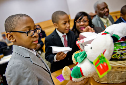 Michael Majette Jr. (left) pulls a stuffed animal out of a basket of toys as his brother Markus sits with their new mother Pam and other brother Mariyo sits with their new father Michael  after finalizing the adoption process at the Fulton County Juvenile Courthouse in Atlanta on Monday, December 29, 2014.