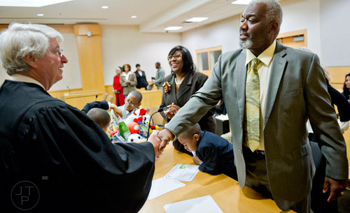 Michael Majette (right) shakes hands with Fulton County Juvenile Court Chief Judge Bradley J. Boyd with his wife Pam after finalizing the adoption of their three sons on Monday, December 29, 2014. 