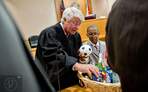 Fulton County Juvenile Court Chief Judge Bradley J. Boyd (left) looks through a basket of toys with Jimitrious Majette after finalizing the adoption of Jimitrious and his two brothers on Monday, December 29, 2014. 