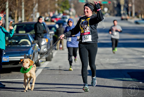 Eliza Martin (center) waves to the crowd as she and her dog Sydney near the finish line during the 10th annual Run with the Dogs Frostbite 5k in Decatur on Saturday, January 10, 2015. 
