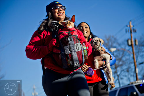 Danielle Perry (left) carries her dog Destin followed closely by Lartesha Chaney carrying her dog Rovi as they near the finish line during the 10th annual Run with the Dogs Frostbite 5k in Decatur on Saturday, January 10, 2015. 