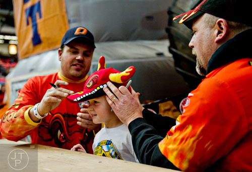 Coen Mays (center) has his hat signed by El Toro Loco team members Chuck Werner (right) and Ty Richardson during the pit party before the start of Monster Jam at the Georgia Dome in Atlanta on Saturday, January 10, 2015. 