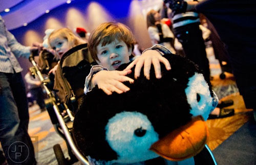Sawyer Ronn (center) holds onto a giant stuffed penguin as he sits in a stroller with his sister Brooklyn during the Party with the Penguins event at the Georgia Aquarium in downtown Atlanta on Saturday, January 17, 2015. 