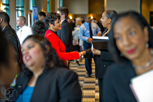 TiQuisha Hines (center left) shakes hands with a potential employee as she talks with job seekers during the 69th Atlanta Diversity, Professional, Veteran, Collegiate Career Fair at the Cobb Galleria Centre in Atlanta on Thursday, January 29, 2015. 