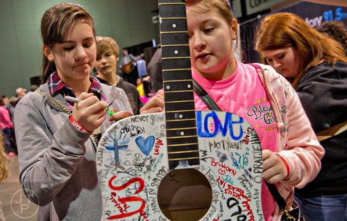 Haley Mendez (left) and Haven Roberson sign a guitar during Jam Zone at the Georgia World Congress Center in Atlanta on Saturday, February 7, 2015. 