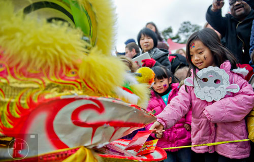 Jenny Cheng (right)) places a donation into a lion's mouth after a performance during the Chinese Lunar New Year celebration in Chamblee on Saturday, February 21, 2015.